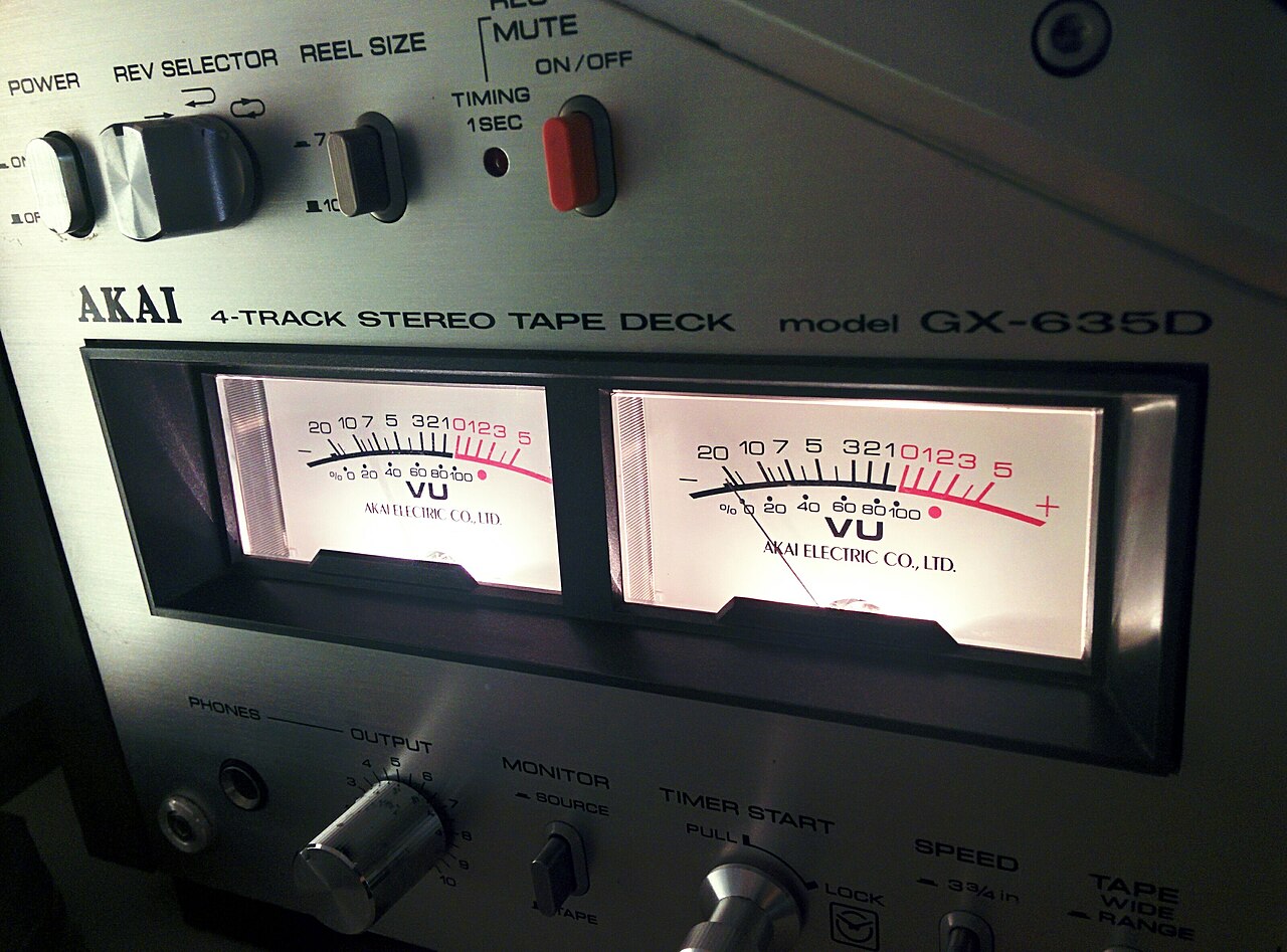 Close-up of two VU meters on a tape deck, one needle pushed into the red.