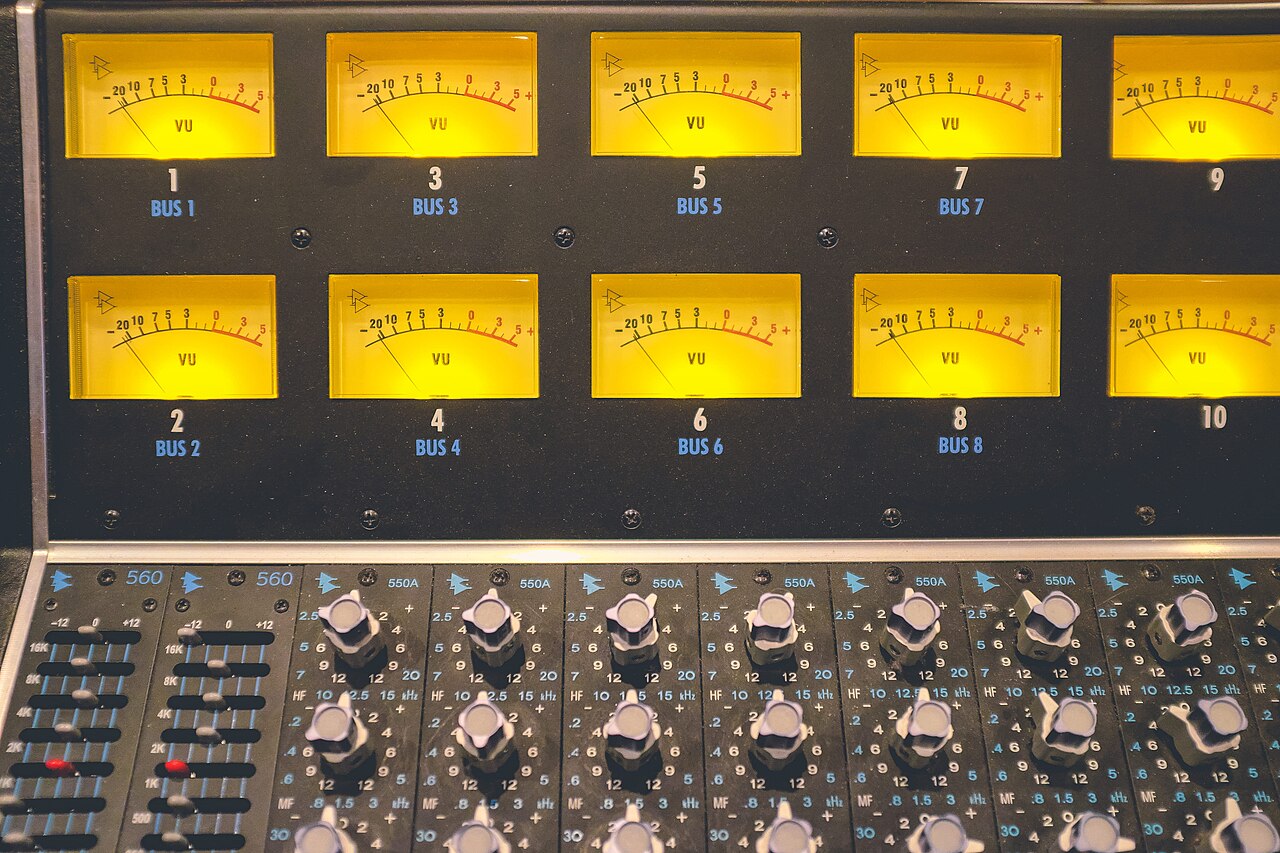 A bank of illuminated VU meters above a row of equaliser modules on a recording console.